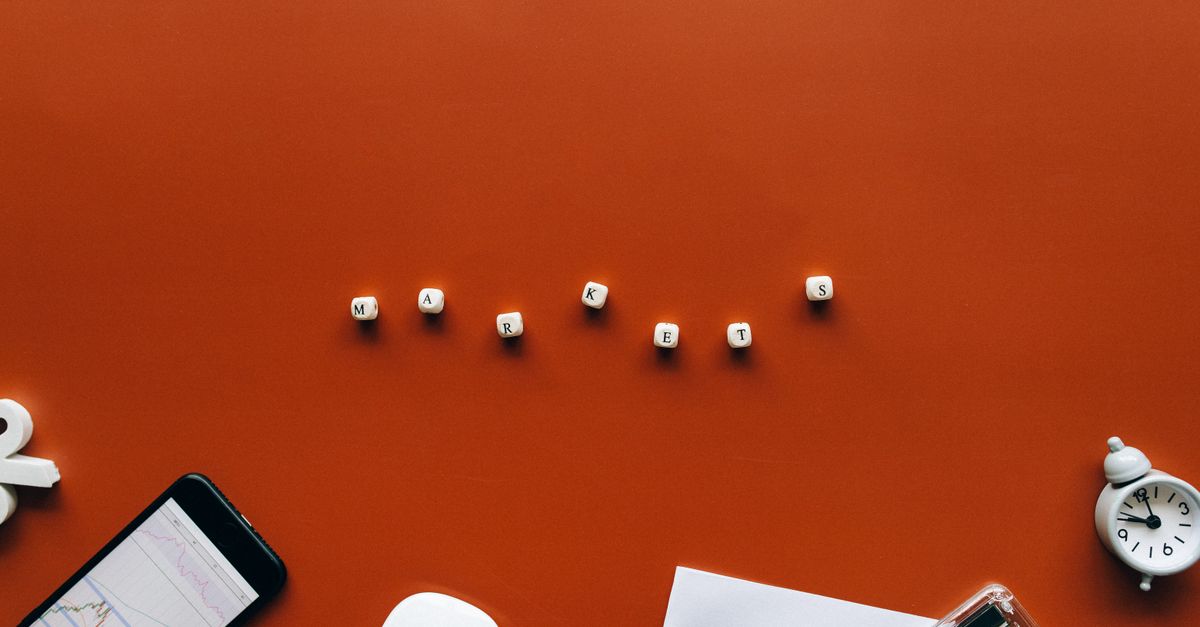 Creative still life with financial tools and the word 'MARKETS' on an orange background.